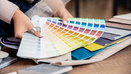 Interior designer decorator choosing wall paint color to match with chooses fabrics for furniture...