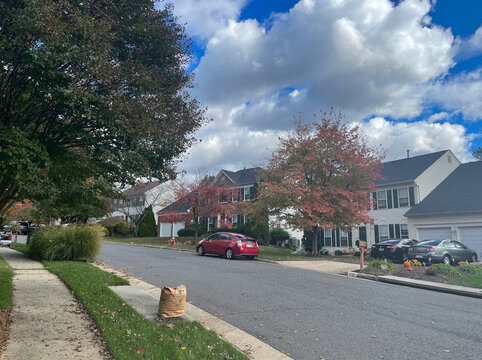 Lorton, Virginia, USA - October 31, 2021: Suburban Homes Surrounded by Trees Changing Colors and Leaves Falling from the Branches on a Bright Autumn Morning