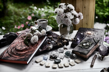Grunge still life with old book of spells, runes amd witch magic objects on ritual table.