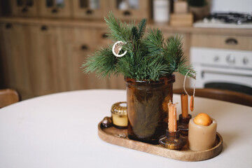Christmas table decor on the kitchen table in eco style, rustic holiday serving with candles and pine tree brunch. Copy space. Beautiful handmade table setting