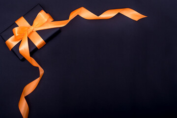  gift i n black paper with orange ribbon on a black background year of the tiger. Top view copy space for text
