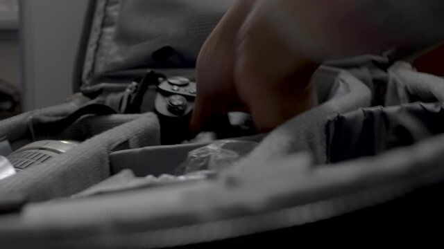 Close up of the hands of a photographer as he packs his lens and camera equipment into his bag in preparation for an upcoming shoot