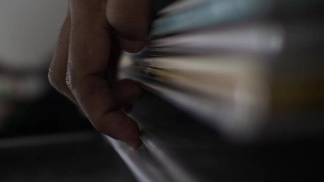 Close up vertical video of a DJ’s fingers browsing through his collection of vinyl albums, uncertain on the beast choice but taking the time to read the cover before making a final decision