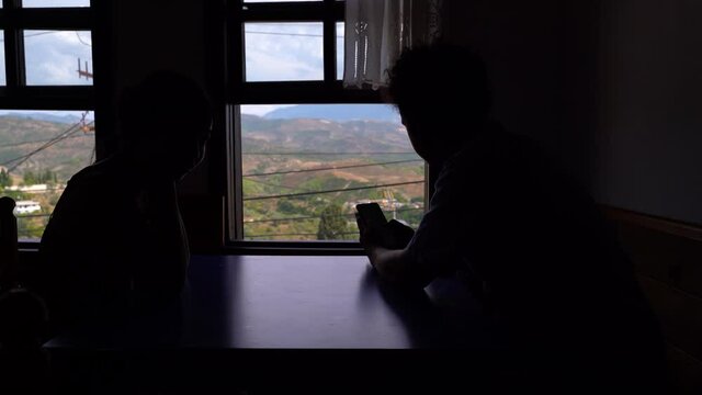 Silhouette of young couple sitting in room with panoramic view outside