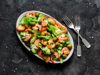 Delicious salad with shrimp, crispy iceberg, crackers and olives on a dark background, top view
