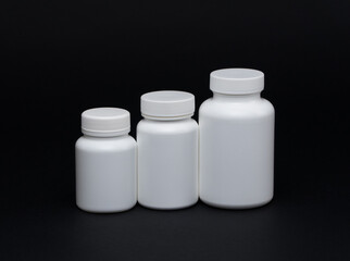 White plastic pill jars on a black background. Isolated