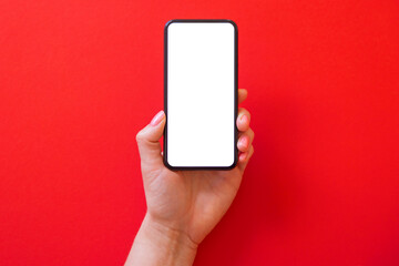 Person holding mobile phone with empty white screen on red background