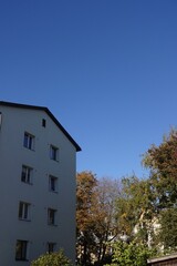 Close up of white apartment house with clear blue sky background with an autumn tree foliage on the right. Pelgulinna, Tallinn, Estonia, Europe. September 2021