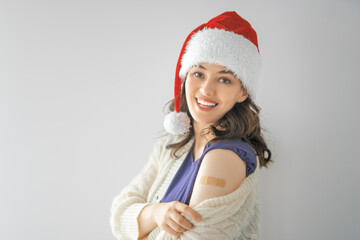 Young woman after vaccination wearing Santa hat