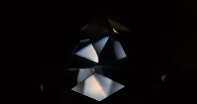 Rotation of the diamond. Reflection of light from the facets of the rhinestone. Close-up of a diamond on a black background
