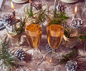 Fototapeta na wymiar Silver candles, lights, cones, glasses of champagne, Christmas decorations on the table.