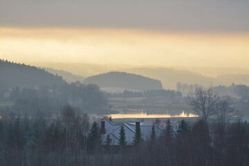 Zimowy wschód słońca nad jeziorem i lasami z mgłą