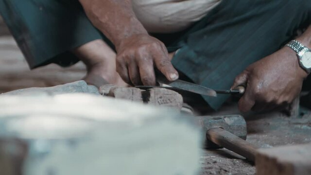 Man sharpening knife by hand using metal file