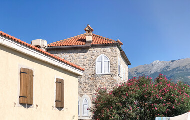 Bright traditional red and orange tiled roofs of houses against the backdrop of beautiful mountains in Montenegro
