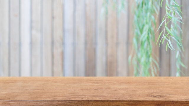 Empty wood table top and blurred wooden wall in garden background with Green leaves - can used for display or montage your products.