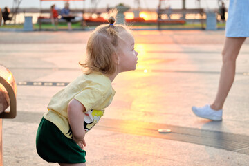 A little girl walks at sunset along the Amur River embankment in the city of Khabarovsk. Russia.