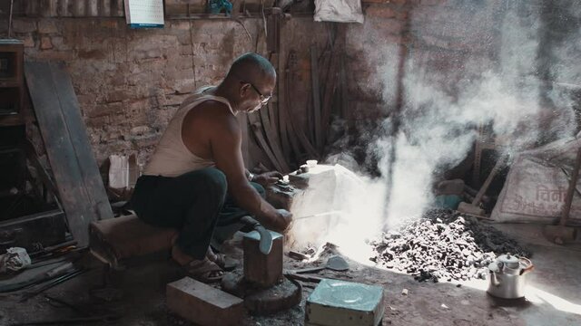 Rural blacksmith worker adding coal to furnace fire