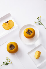 Topview of persimmon and seeds in the petri dish with transparent podium on white background. Research and develop cosmetics in laboratory for advertising
