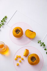 Topview of persimmon and seeds in the petri dish with transparent podium on white background. Research and develop cosmetics in laboratory for advertising
