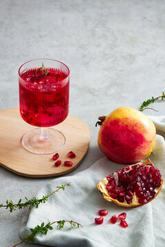 Pomegranate juice in a wooden dish with pomegranate seed with grey  background and a napkin decoration  , for food adverting , front view , green leaf