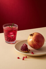 Pomegranate juice in a white dish with pomegranate seed with red background , for food adverting , front view 