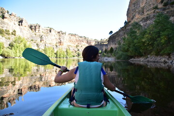 young woman paddling in a canoe over the waters of las hoces del rio duratón