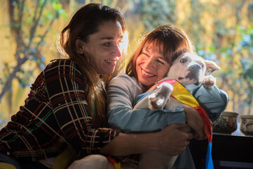 LGBT lesbian couple sharing a happy romantic moment for Christmas at home with a dog.