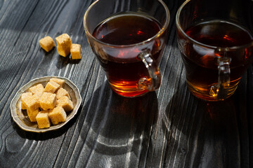 Two cups with black tea and brown sugar