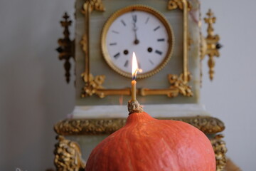 small burning candle. the flame of a melted candle on the background of an old clock