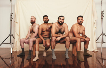 Group of body positive men sitting shirtless in a studio