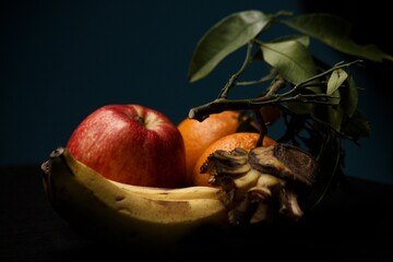 apple orange and bananas on black background