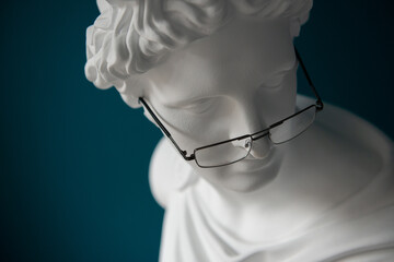 Plaster statue head with glasses. Antiquity and modernity. Myopia and hyperopia treatment concept