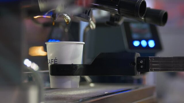 Close-up of coffee machine pours beverage in the cup.