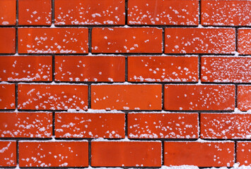 Red brick wall with snow on it after snowfall.