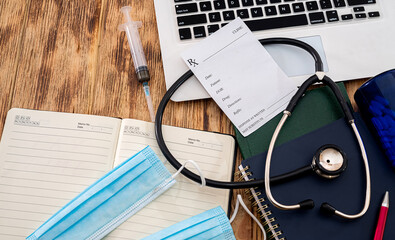 notebook with stethoscope prescription on keyboard with notepad on desk