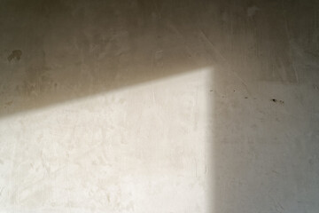 The light from the window hits the concrete wall inside the room without renovation. Concept of an apartment without finishing works, preparation for renovation.