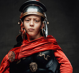 Dressed in legionary clothing cheerful boy in dark background