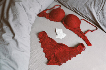 lingerie set with condoms on bed as safe sex and contraception concept