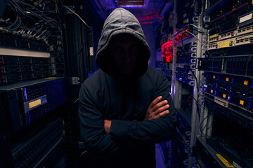 Gloomy man standing between racks with computer equipment