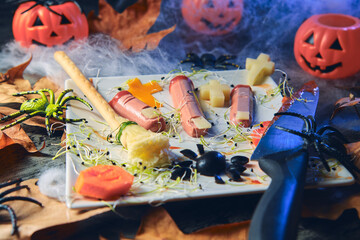 Frankfurt with fingers cut by a knife simulating a halloween scenario, decorated with harry potter's broom, black olives, pumpkins, spiders, teranyina and cemetery and cheese chain