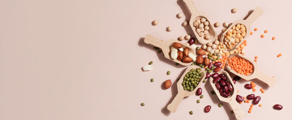 Vegan protein source. Beans, peas, chickpeas, lentils, mung bean, peanut in wooden spoon on beige background. - obrazy, fototapety, plakaty