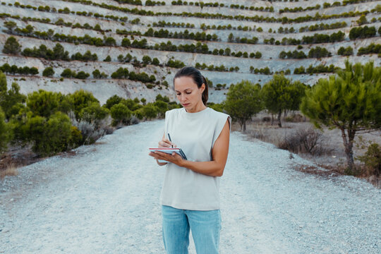 Female scientist writing in book while standing in old mine