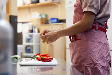 Obraz na płótnie Canvas 飲食店のキッチンで野菜を切る女性シェフの手元