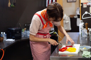 飲食店のキッチンでパプリカを切る女性