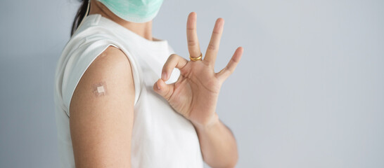 woman showing OK sign with bandage after receiving covid 19 vaccine. Vaccination, herd immunity, side effect, booster, vaccine passport and Coronavirus pandemic - obrazy, fototapety, plakaty