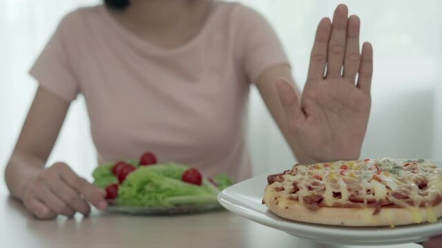 Women refuse to eat pizza cake and eat salad for diet and control weight. Healthy women choose vegetables and fruit on main meal for diet and weight loss concept. Diet concept.