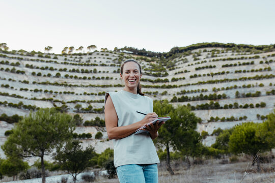 Happy female expertise writing in book while working at old mine