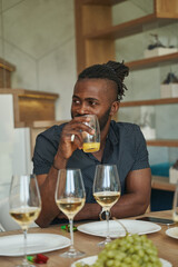 African American guy sitting at table and drinking juice