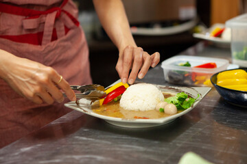 カレーライスの盛り付けをする女性料理人