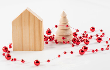 Christmas composition. Wooden house, christmas tree, red garland on a white background. Accessories, decorations for Christmas. Winter and christmas design template greeting card.